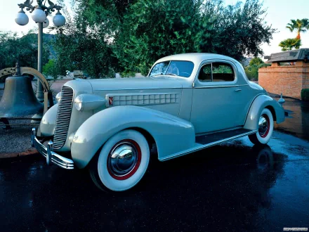 HD desktop wallpaper featuring a classic 1936 Cadillac V8 Series 70 Coupe parked outdoors, showcasing its vintage design and smooth, light blue body.