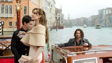 HD PC desktop wallpaper from the movie The Tourist: an elegant woman in a cape stands on a Venetian quay while two men in a boat watch on the canal.