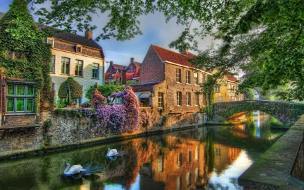 Scenic view of historic man-made buildings along a calm river in Nuremberg, Germany, framed by lush greenery under a clear sky.