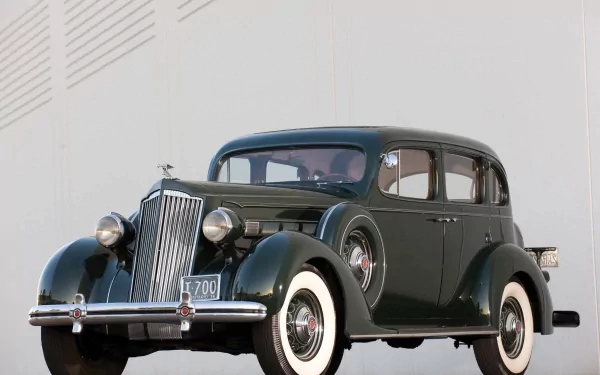 HD PC desktop wallpaper/background: vintage Packard 120 B vehicle in dark green with whitewall tires and chrome trim parked against a pale wall.