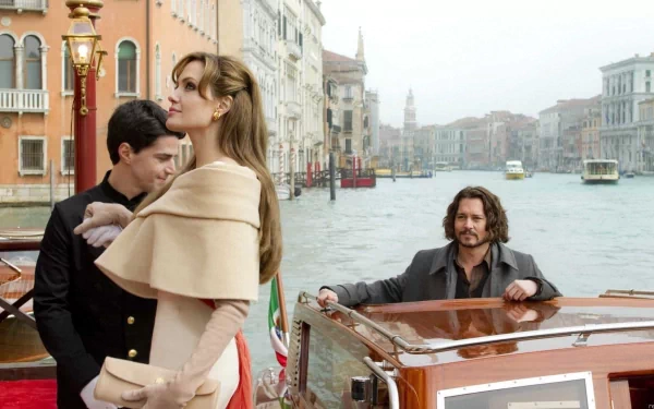 HD PC desktop wallpaper from the movie The Tourist: an elegant woman in a cape stands on a Venetian quay while two men in a boat watch on the canal.