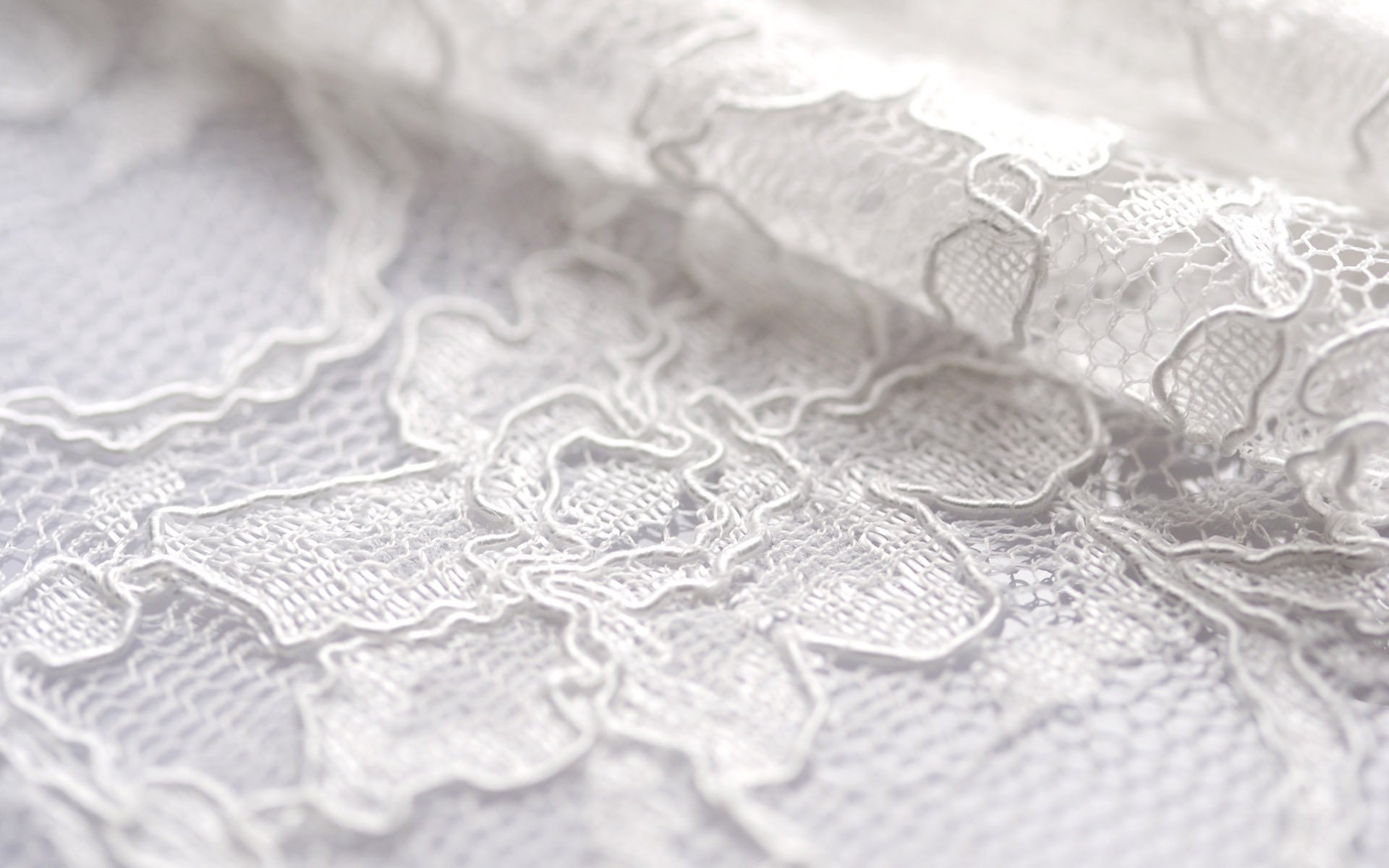 Abstract close-up of delicate white lace fabric, showcasing intricate patterns and textures, designed as an HD PC desktop wallpaper and background.