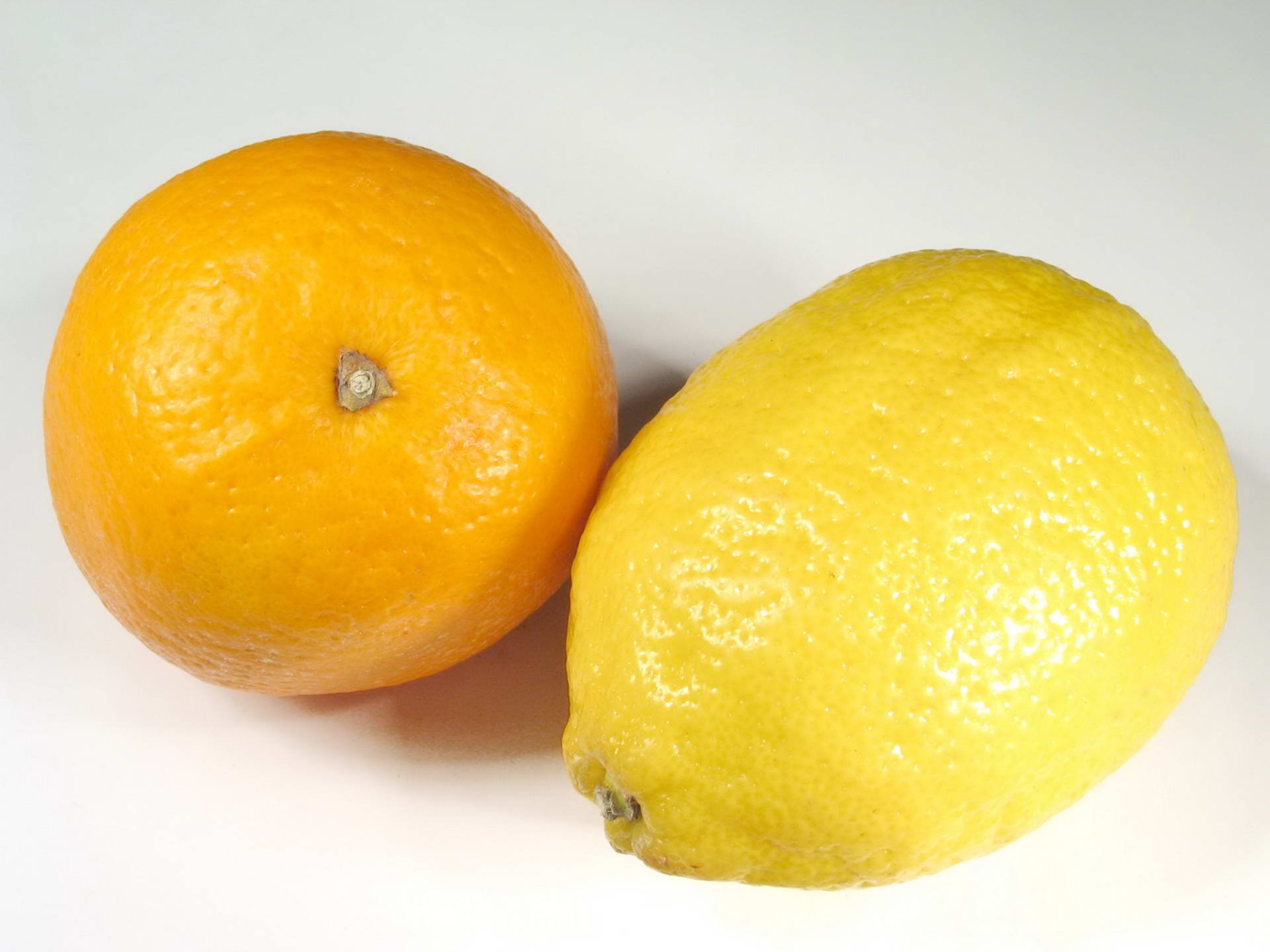 HD PC desktop wallpaper and background showing a close-up of an orange and a lemon on a white surface, bright food, fruit still life.