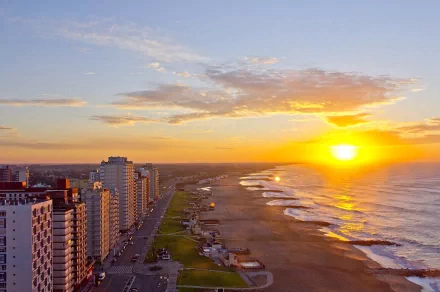 HD desktop wallpaper showing a man-made beachfront skyline at Miramar during a vibrant sunset with calm ocean waves and clear skies.