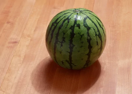 HD desktop wallpaper featuring a fresh whole watermelon on a wooden surface, highlighting vibrant green stripes and smooth texture.