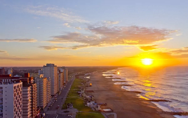 HD desktop wallpaper showing a man-made beachfront skyline at Miramar during a vibrant sunset with calm ocean waves and clear skies.