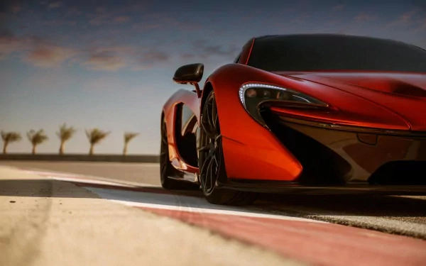 HD desktop wallpaper featuring a sleek orange McLaren P1 supercar on a racetrack, set against a backdrop of palm trees and a vibrant sky.
