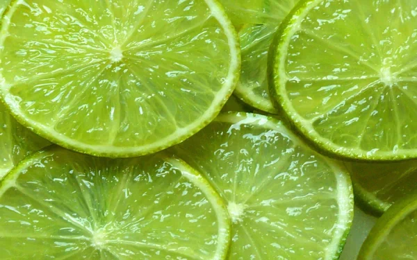 Close-up HD desktop wallpaper of fresh lime slices with dewy texture, highlighting vibrant green hues and juicy food details.