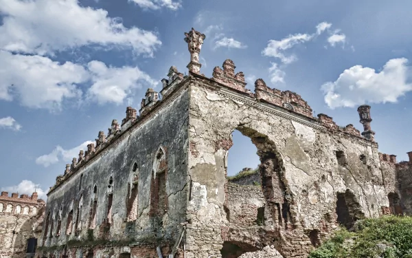 4K Ultra HD wallpaper of an ancient man-made ruin with weathered stone walls and intricate details under a bright blue sky with scattered clouds.
