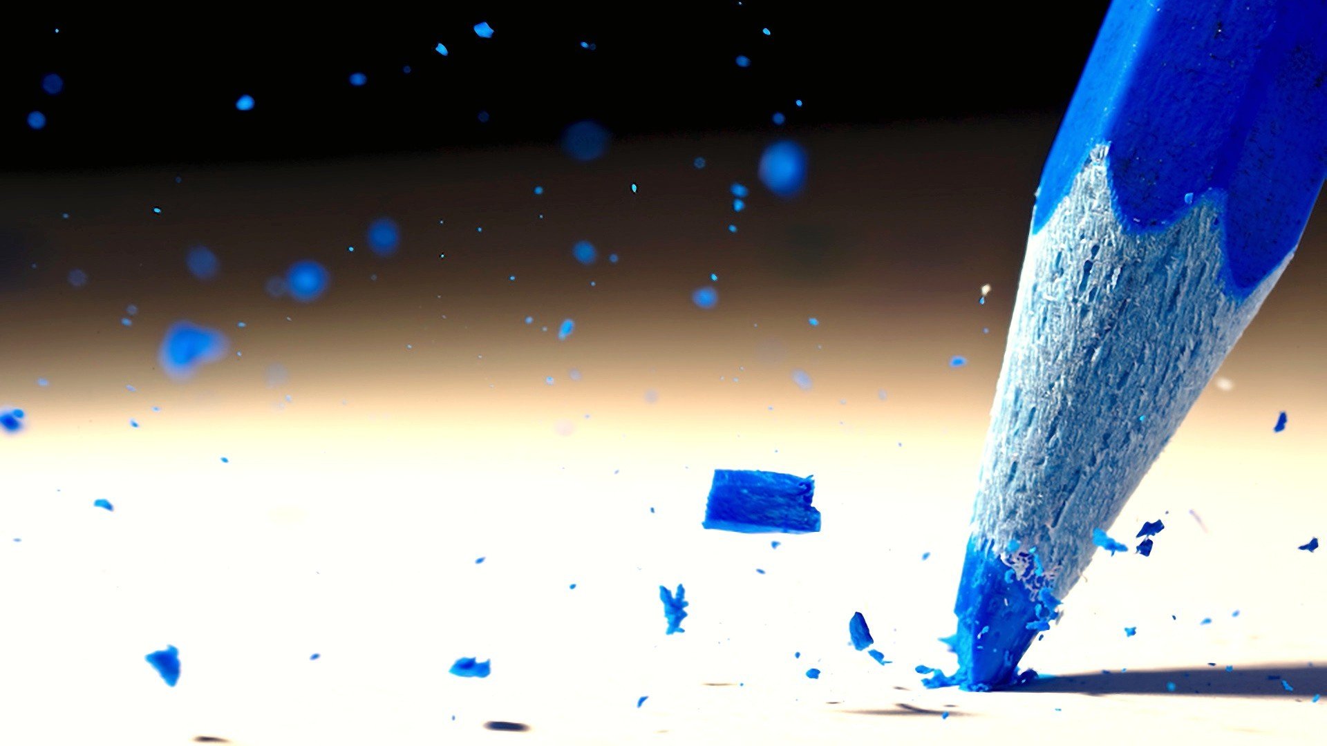 HD desktop wallpaper featuring a close-up photography of a sharpened blue pencil with scattered blue shavings on a light surface.