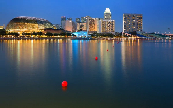 HD desktop wallpaper showcasing Singapore’s man-made skyline and waterfront illuminated at dusk with calm water reflecting city lights.