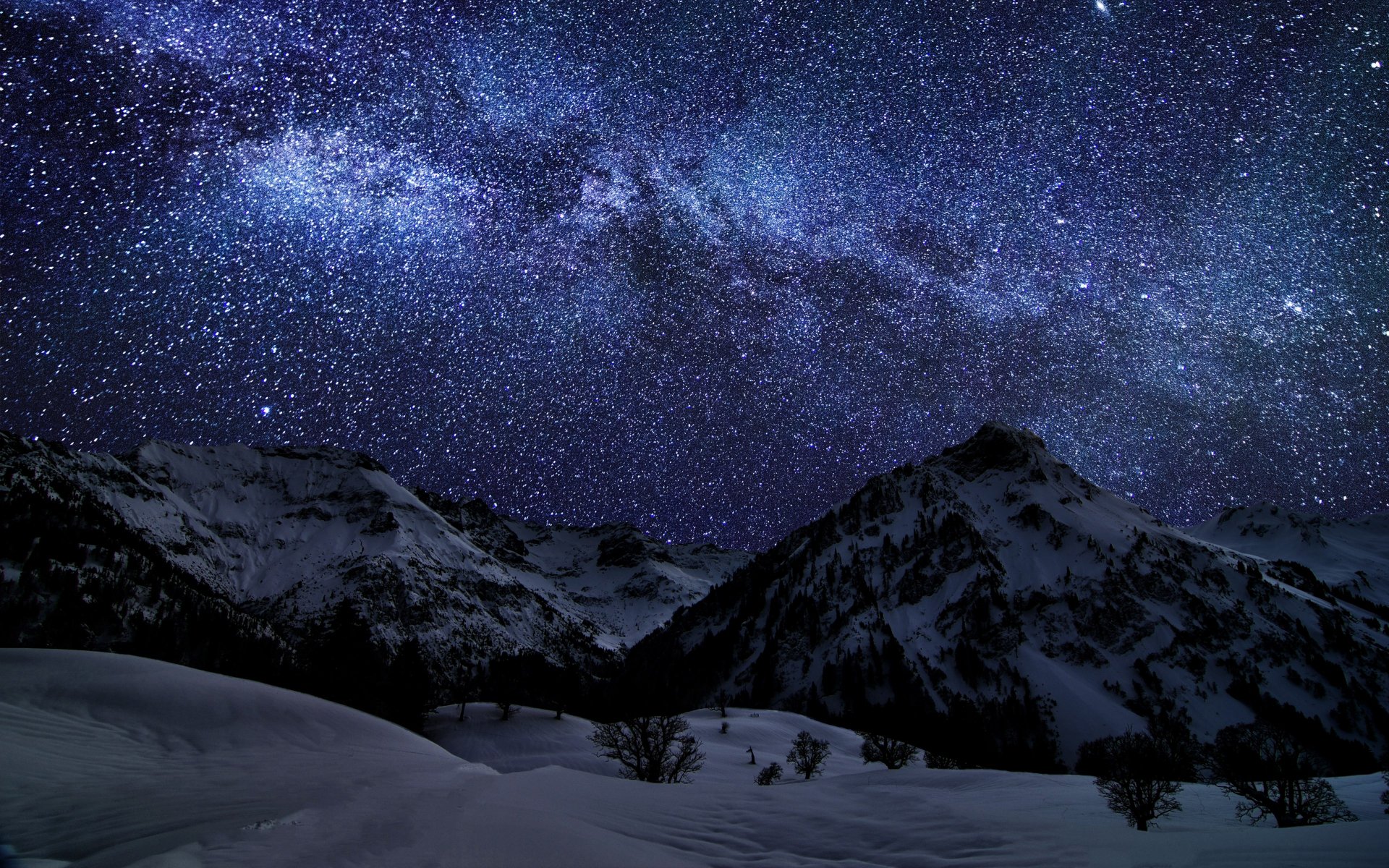 4K Ultra HD wallpaper of snow-covered mountains beneath a star-filled night sky with the Milky Way stretching across, showcasing stunning natural beauty.