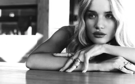 Black-and-white HD desktop wallpaper featuring celebrity Rosie Huntington-Whiteley resting her arms on a surface with a soft, contemplative expression.