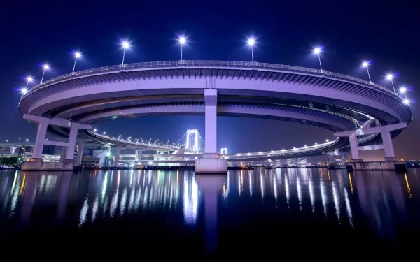 HD desktop wallpaper of Tokyo’s Rainbow Bridge at night, showcasing its illuminated circular man-made structure reflecting on the water in Japan.