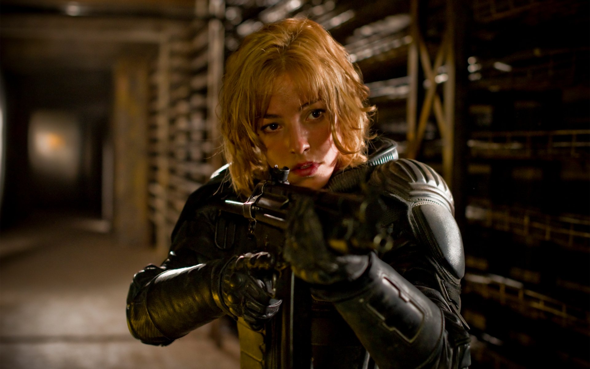 HD PC desktop wallpaper from the movie Dredd, showing a focused character aiming a firearm in a dimly lit corridor.