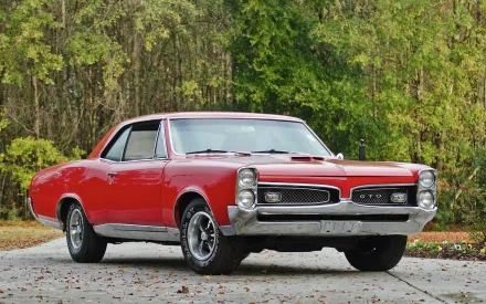 A vibrant red 1967 Pontiac GTO parked outdoors, captured in high definition for a PC desktop wallpaper and background.