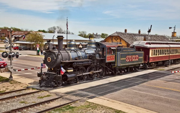 4K Ultra HD PC desktop wallpaper and background: vintage steam train vehicle crossing a small-town station at a level crossing under a blue sky.