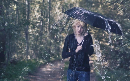 A person holding a black umbrella in the rain on a forest path, captured in a high-definition photography image used as a PC desktop wallpaper.