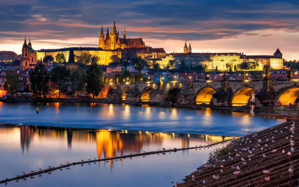 A stunning HD wallpaper of Prague at dusk, featuring the iconic skyline with the castle and Charles Bridge reflected in the calm water, creating a captivating man-made landscape.
