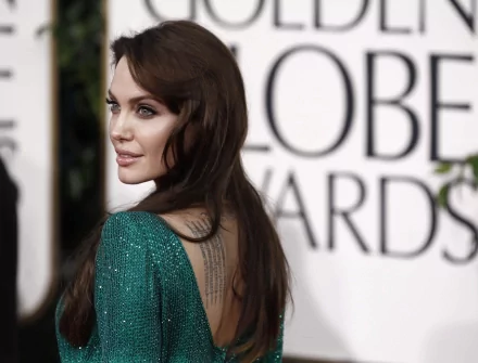 HD desktop wallpaper of Angelina Jolie at an awards ceremony, wearing a green dress with an elegant back tattoo visible.