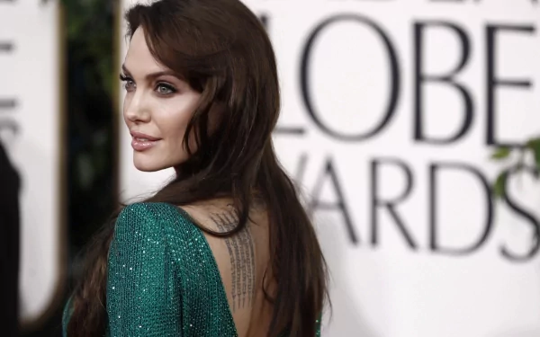 HD desktop wallpaper of Angelina Jolie at an awards ceremony, wearing a green dress with an elegant back tattoo visible.