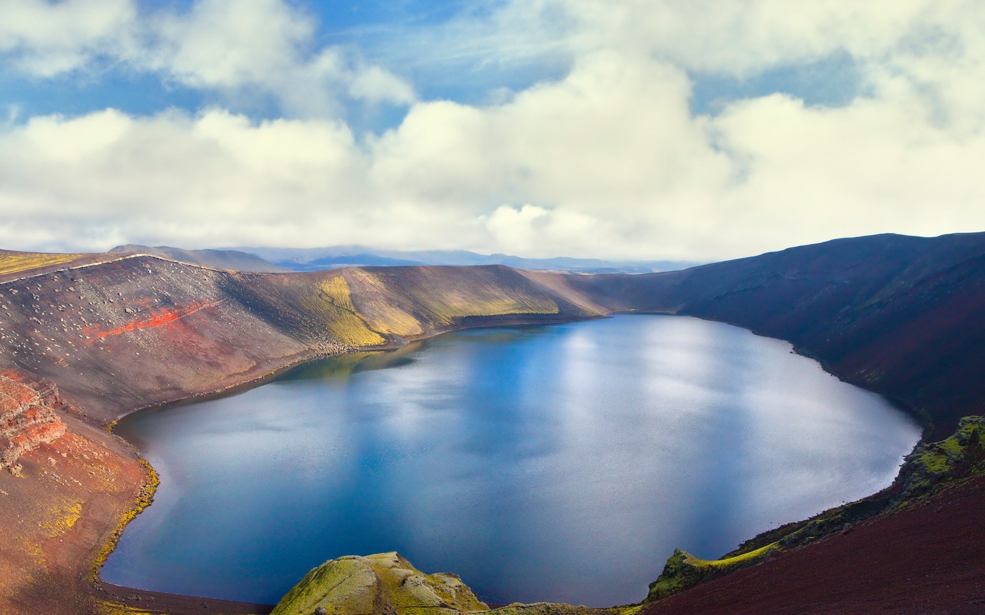 HD PC desktop wallpaper depicting a serene lake surrounded by hills under a partly cloudy sky in a nature setting.
