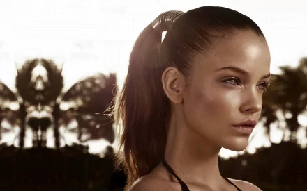 A stunning HD wallpaper featuring celebrity Barbara Palvin, showcasing her profile against a soft, tropical backdrop with palm silhouettes and warm lighting.