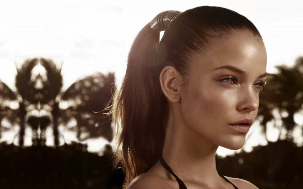 A stunning HD wallpaper featuring celebrity Barbara Palvin, showcasing her profile against a soft, tropical backdrop with palm silhouettes and warm lighting.