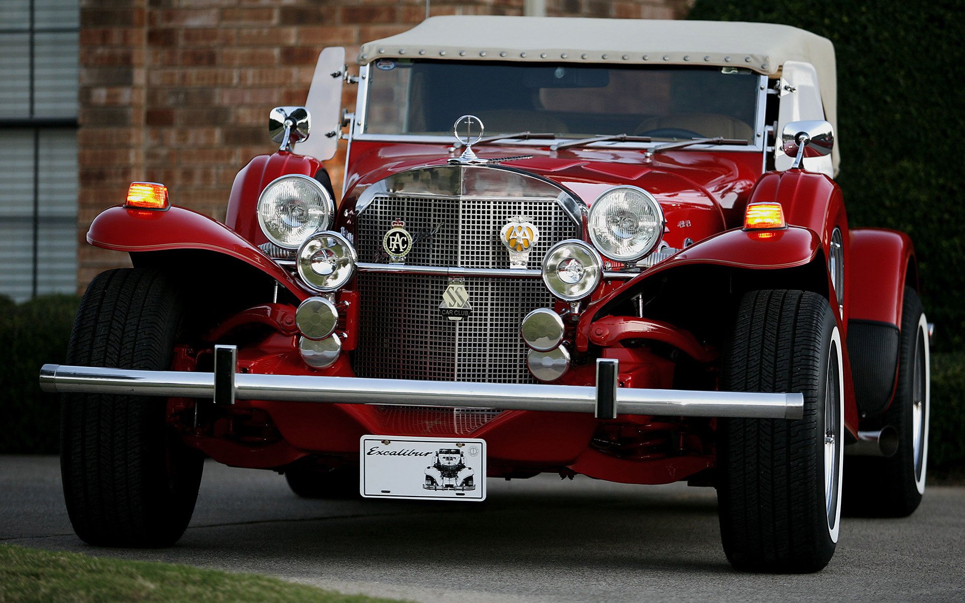 A striking 1976 Excalibur Series III Phaeton, featuring a vibrant red exterior and classic design elements, showcased as an HD PC desktop wallpaper and background.