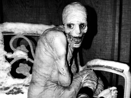 A dark, creepy HD desktop wallpaper featuring a skeletal figure sitting on a bench, exuding an eerie atmosphere with its haunting smile and stark contrasts.