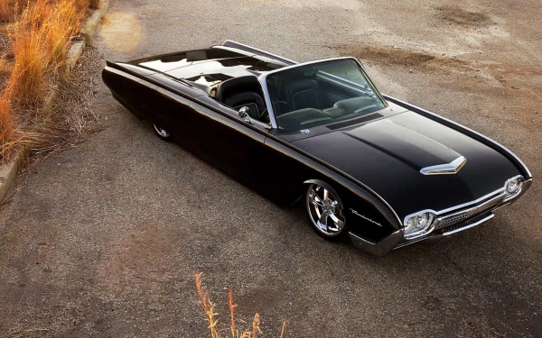 HD PC desktop wallpaper featuring a sleek black Ford Thunderbird convertible parked on a rustic road beside dry grass.