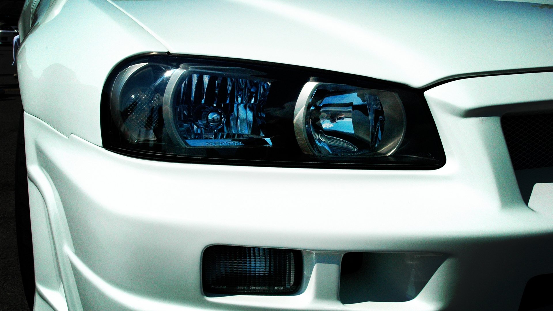 Close-up of a white Nissan Skyline headlight, featured as an HD PC desktop wallpaper and background.