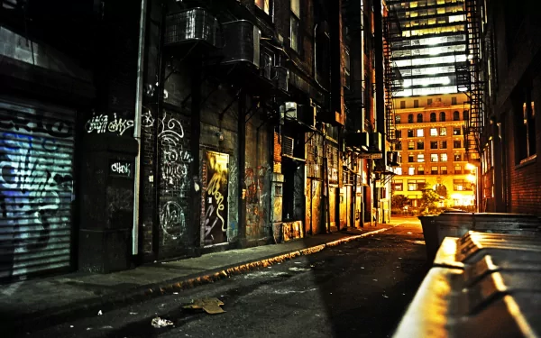 HD desktop wallpaper of a dimly lit man-made alleyway with graffiti-covered walls and illuminated buildings in the background.