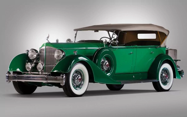 HD desktop wallpaper featuring a classic green Packard Twelve vintage vehicle with whitewall tires and a tan convertible roof against a neutral background.