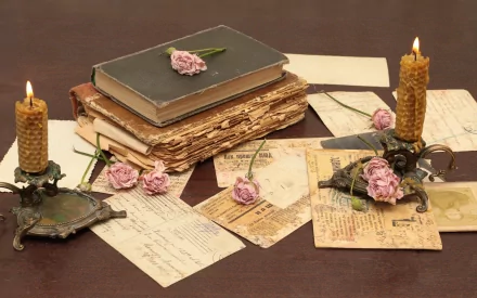 A vintage-inspired arrangement featuring a stack of old books, handwritten letters, and candles, accented with soft pink flowers, creating an inviting and nostalgic atmosphere.