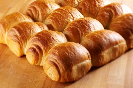 A warm assortment of freshly baked bread rolls, showcasing a golden-brown crust, arranged neatly on a wooden surface. This 4K Ultra HD image captures the essence of baking and delicious food.