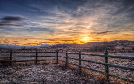 HD desktop wallpaper featuring a man-made wooden fence stretching across a frosty field under a vibrant sunrise sky.