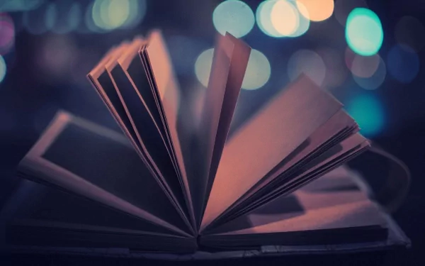 An HD desktop wallpaper featuring an open book with pages fanned out against a blurred background of colorful lights.