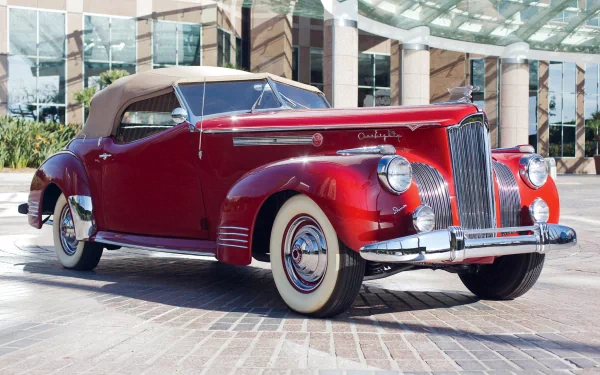 A classic red Packard 180 convertible parked in front of modern glass buildings, displayed as a high-definition PC desktop wallpaper and background.