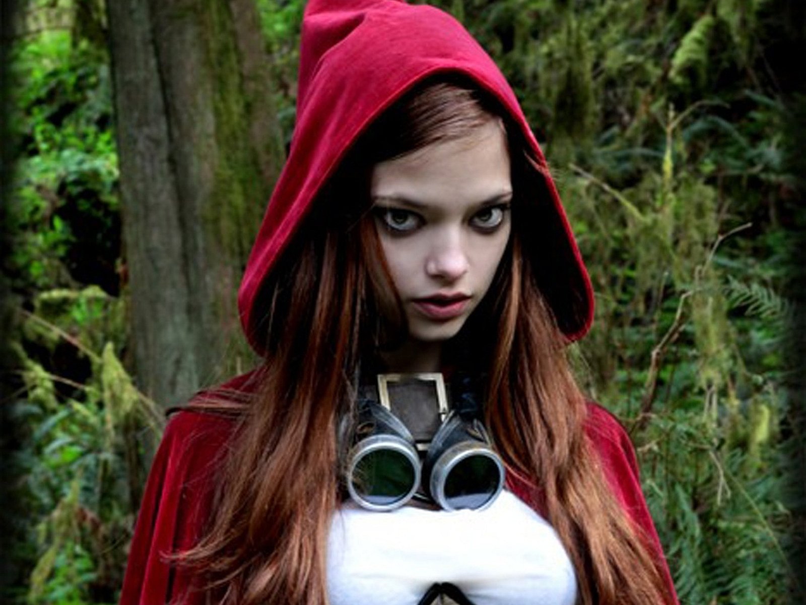 A woman in cosplay wears a striking red hood and goggles, set against a backdrop of lush greenery. This image serves as an HD PC desktop wallpaper and background.