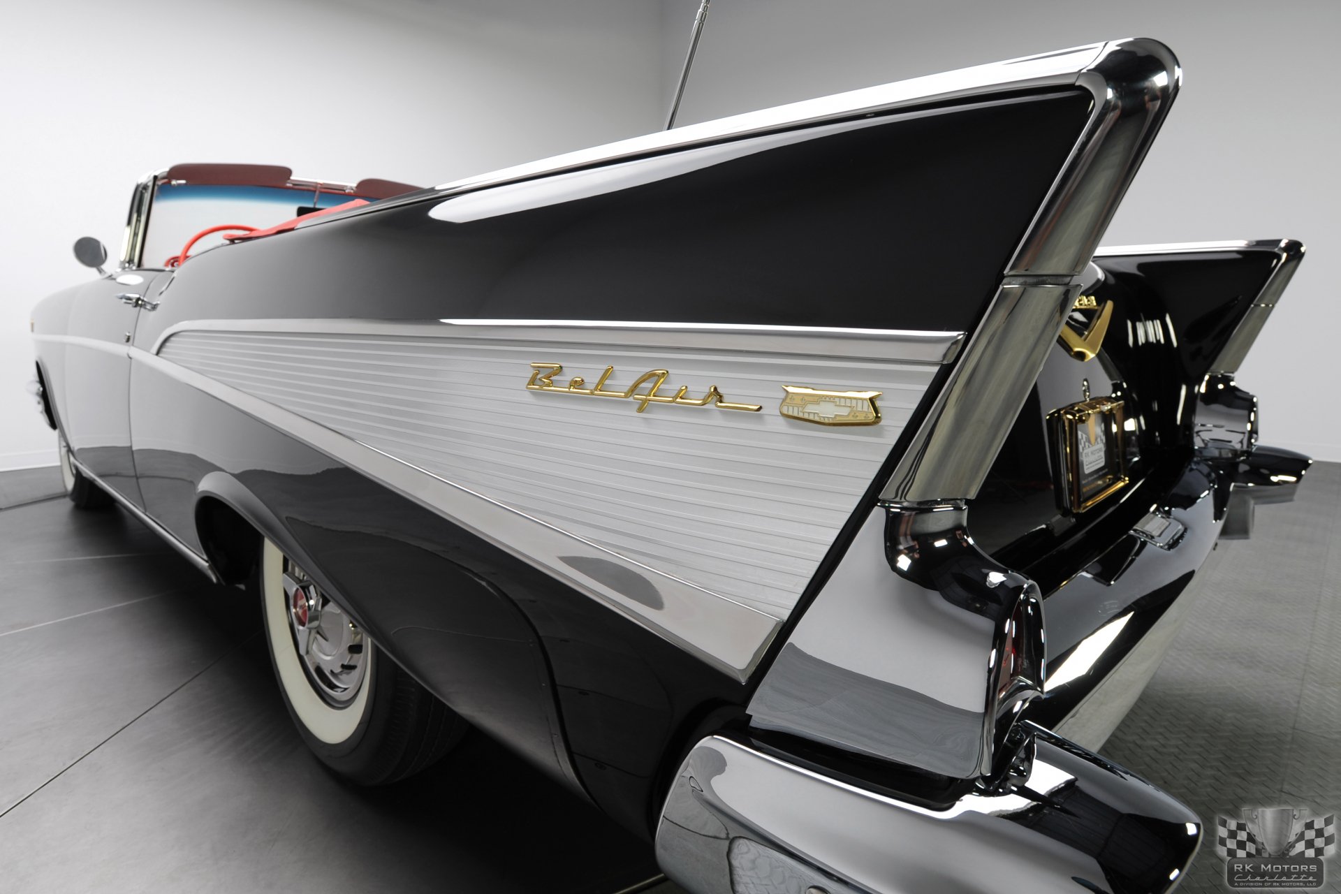 Rear three-quarter view of a 1957 Chevrolet Bel Air vehicle, chrome fins and tail emblem on a black-and-white convertible, shown as a 2K Quad HD PC desktop wallpaper/background.