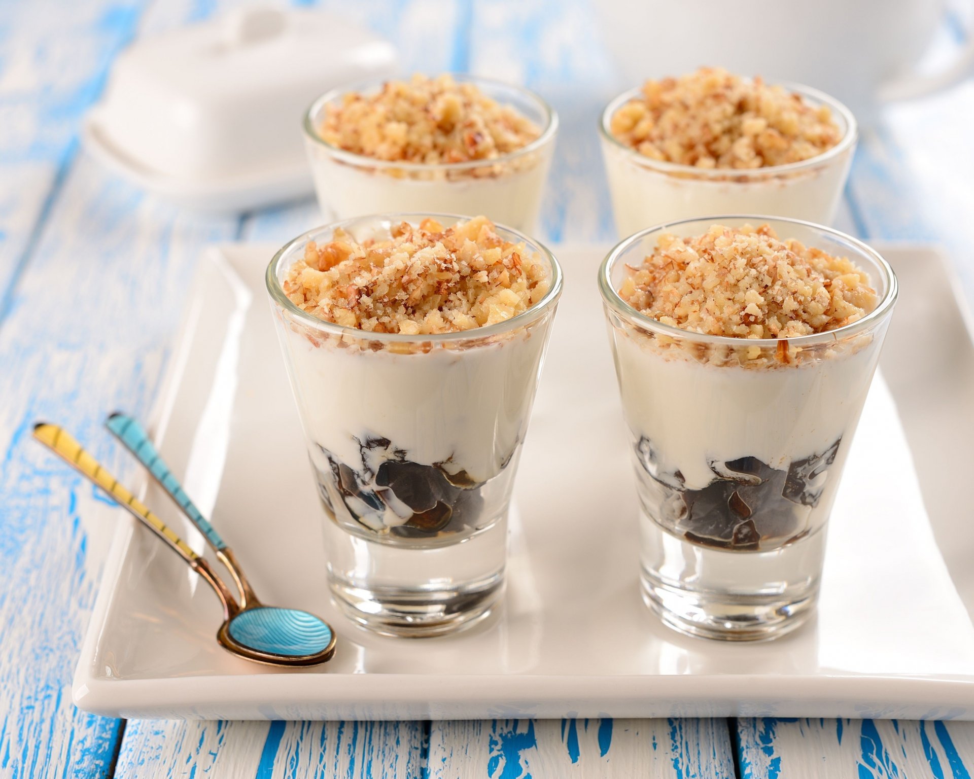 Close-up of four dessert parfaits with creamy layers and crumbled topping in clear glasses, showcased as a 4K Ultra HD PC desktop wallpaper background.
