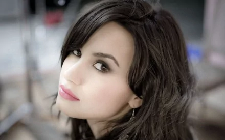 A close-up of Demi Lovato, showcasing her striking features and expressive gaze, serves as an engaging HD desktop wallpaper and background for music enthusiasts.