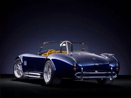 HD desktop wallpaper featuring a sleek blue Shelby Cobra AC vehicle showcased against a dark background, highlighting its classic design and polished chrome details.