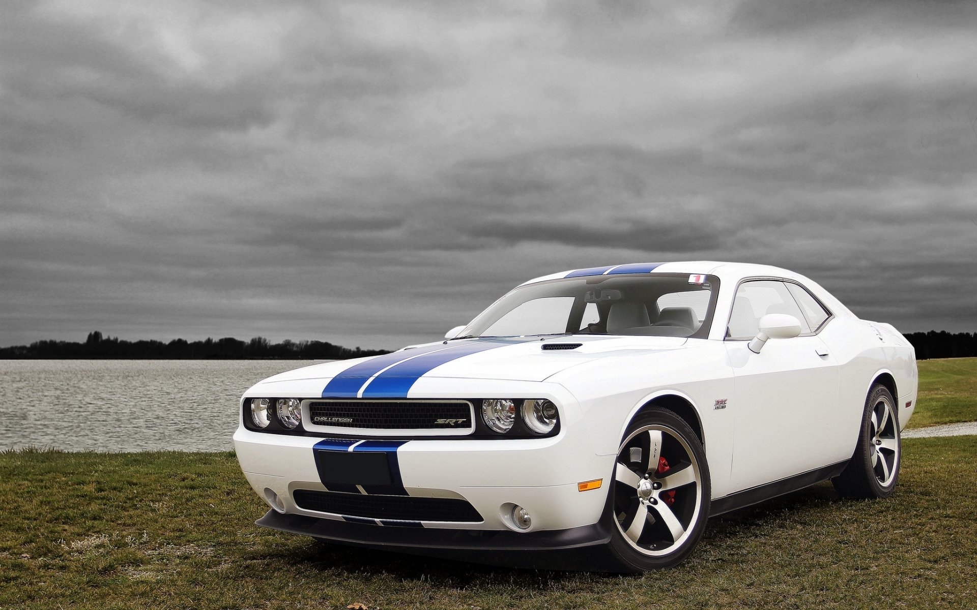 HD PC desktop wallpaper of a white Dodge Challenger SRT with blue racing stripes parked by a lakeshore under a dramatic cloudy sky.