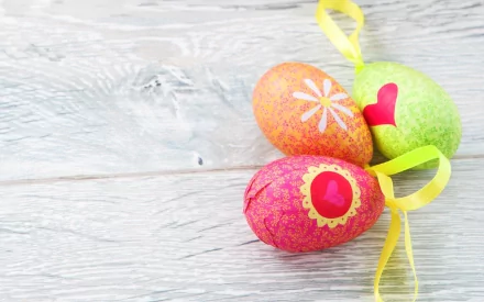 Colorful Easter eggs adorned with decorative patterns are displayed on a rustic wooden background, creating a festive holiday atmosphere. This HD wallpaper captures the spirit of Easter beautifully.