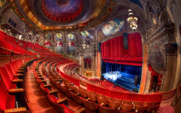 HD desktop wallpaper showcasing the ornate interior of a man-made opera house with red seats, intricate architectural details, and a grand stage under a vibrant ceiling.