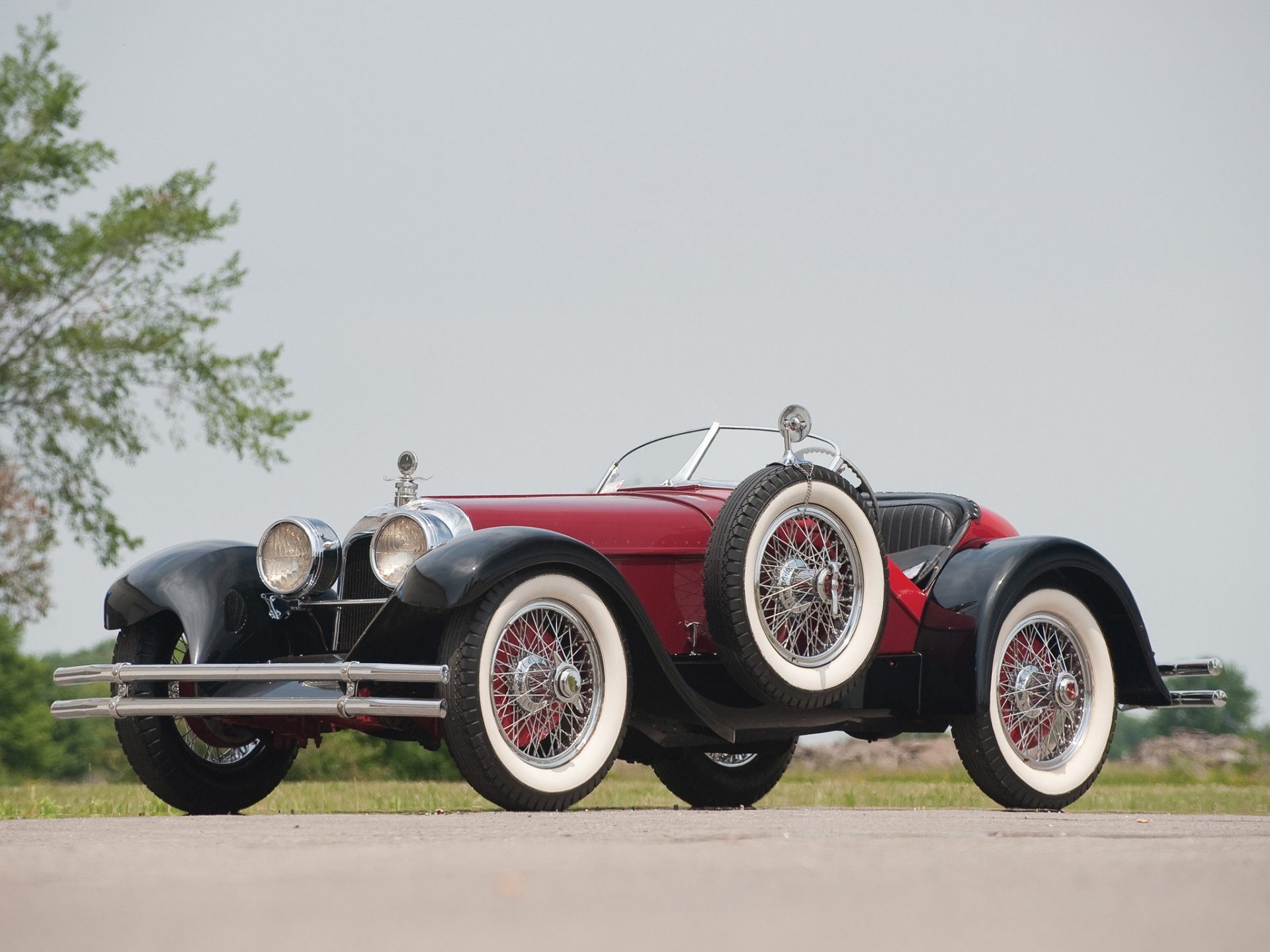 Red 1924 Duesenberg Model A Speedster with whitewall tires on a road, framed as an HD PC desktop wallpaper background.