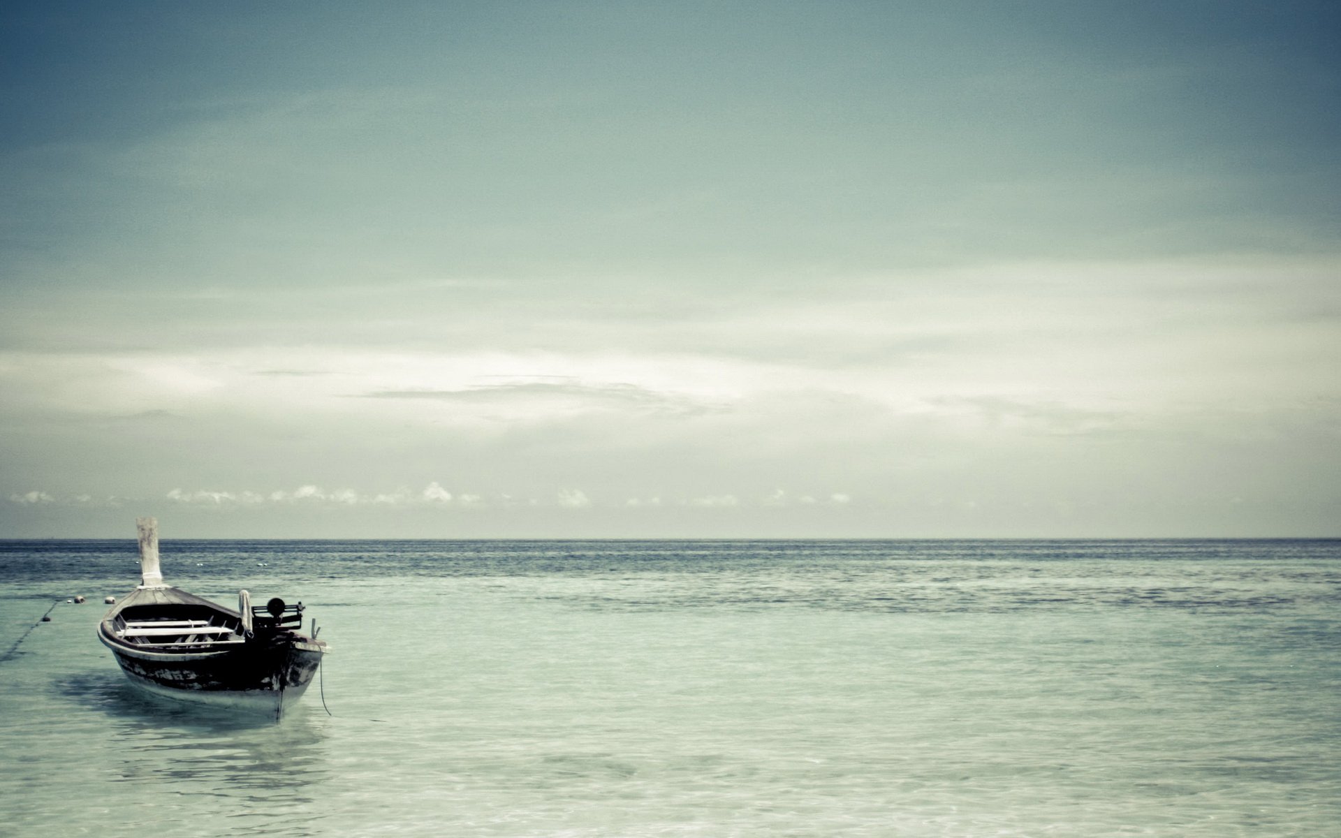 HD PC desktop wallpaper showing a calm sea with a single boat near the shore under a cloudy sky, highlighting a serene coastal vehicle scene.