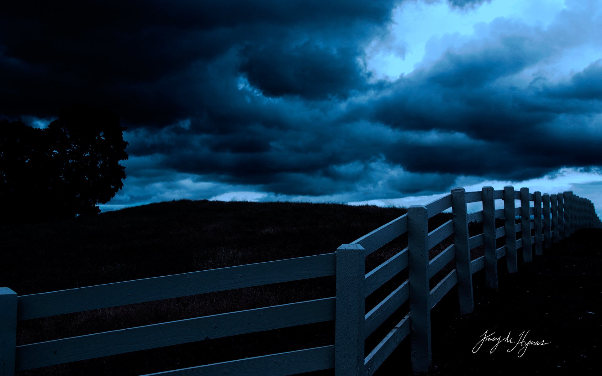 HD PC desktop wallpaper — white man-made fence leading across a dark, moody landscape beneath brooding storm clouds.